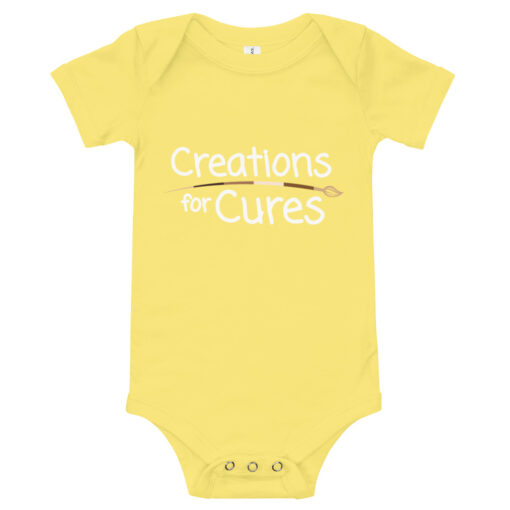 a yellow short-sleeve baby one-piece featuring the Creations for Cures with diverse skin tone paintbrush