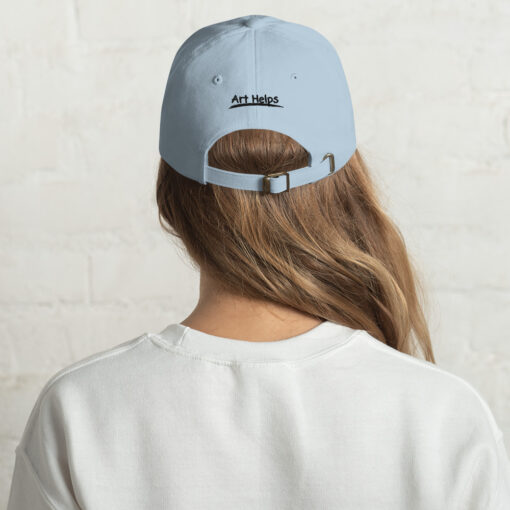 back view of a person wearing a light blue "dad" hat featuring the phrase "Art Helps" in black above the adjustment strap
