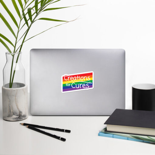a sticker featuring the Creations for Cures logo over a rectangular rainbow graphic