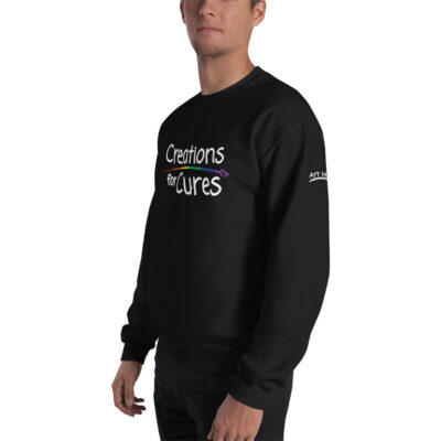 a person wearing a black crew neck sweatshirt featuring the Creations for Cures logo with rainbow-striped paintbrush