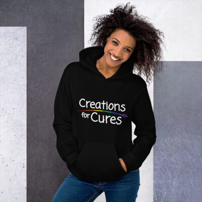 a person wearing a black hoodie featuring the Creations for Cures logo with rainbow-striped paintbrush