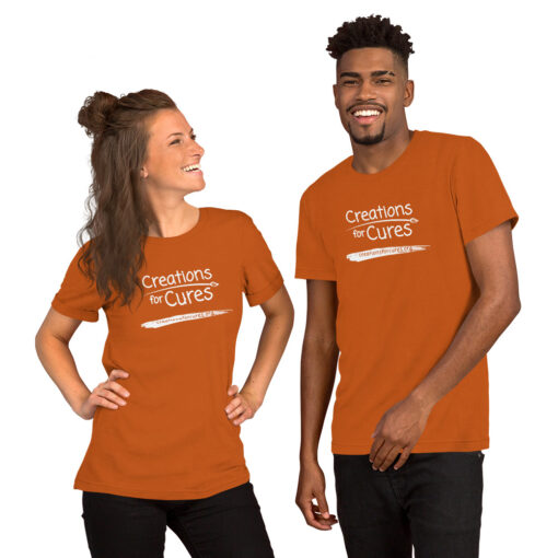 two people wearing autumn orange t-shirts featuring the Creations for Cures logo in white