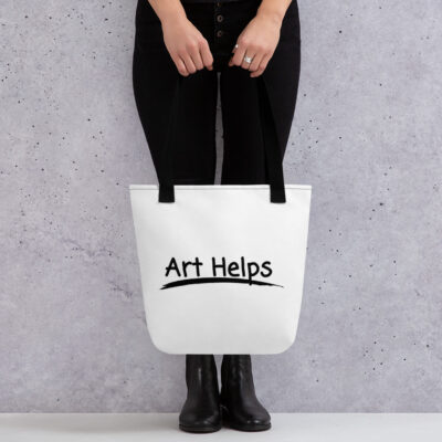 a canvas tote bag with black handles featuring black artwork of the phrase "Art Helps" with a brushstroke under it