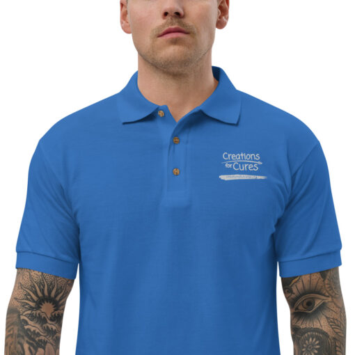a person wearing a royal blue polo featuring the Creations for Cures logo