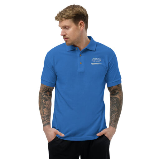 a person wearing a royal blue polo featuring the Creations for Cures logo