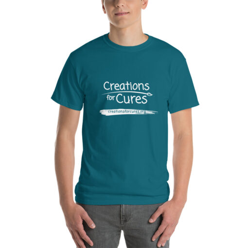 a person wearing a Galapagos blue t-shirt featuring the Creations for Cures logo in white