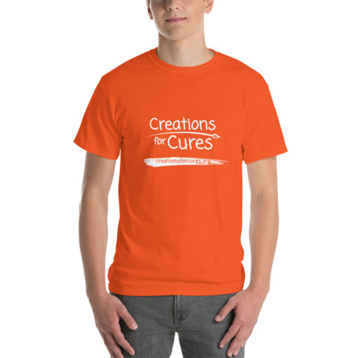 a person wearing an orange t-shirt featuring the Creations for Cures logo in white