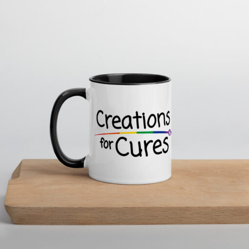 a white ceramic mug with black handle and interior featuring the Creations for Cures logo