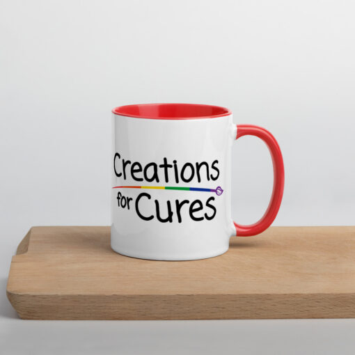 a white ceramic mug with red handle and interior featuring the Creations for Cures logo