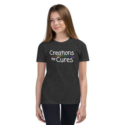 a person wearing a heather dark grey t-shirt featuring the Creations for Cures logo with a rainbow-colored paintbrush