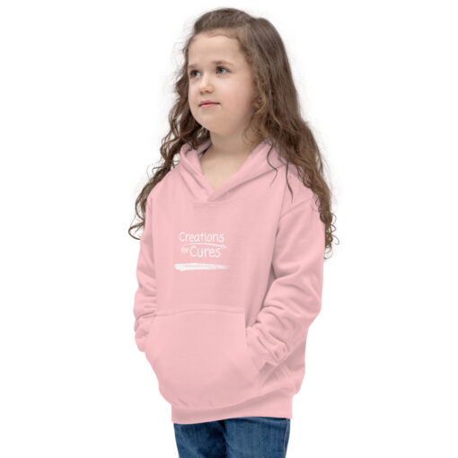 a person wearing a kids size baby pink hoodie featuring the Creations for Cures logo