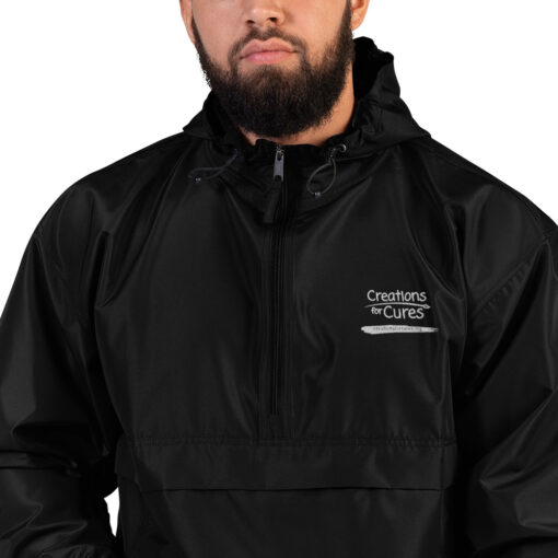 a person wearing a black Champion pullover jacket with the Creations for Cures logo on it