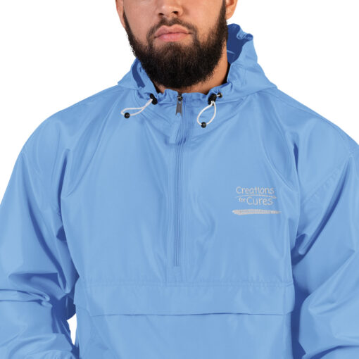 a person wearing a blue Champion pullover jacket with the Creations for Cures logo on it