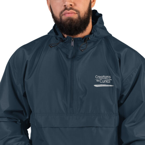 a person wearing a navy Champion pullover jacket with the Creations for Cures logo on it