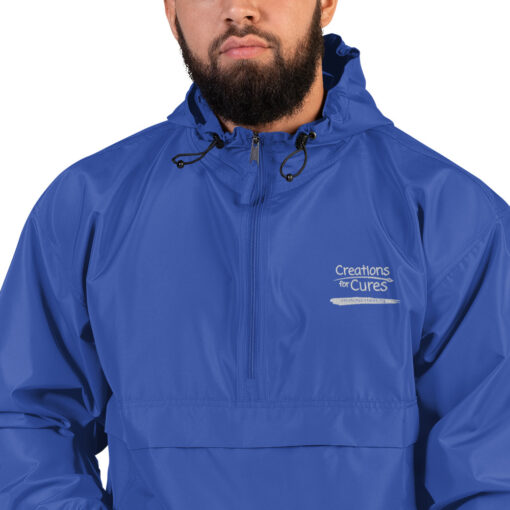 a person wearing a royal blue Champion pullover jacket with the Creations for Cures logo on it