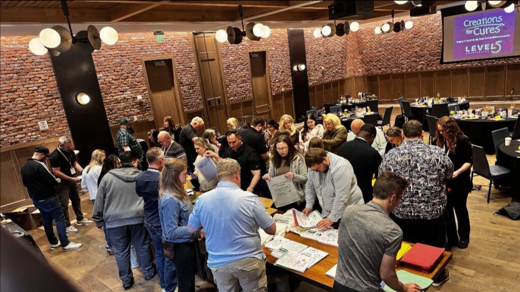 overhead view of people interacting with Creations for Cures materials at a Level5 Hospitality event for Creations for Cures
